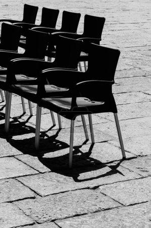 Photo for A vertical shot of many black empty chairs on a cobblestone - Royalty Free Image