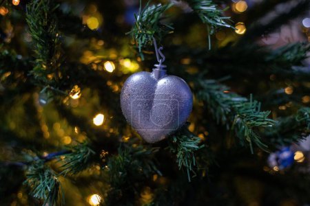 Photo for The close-up view of a heart-shaped silver ornament hung from the Christmas tree - Royalty Free Image
