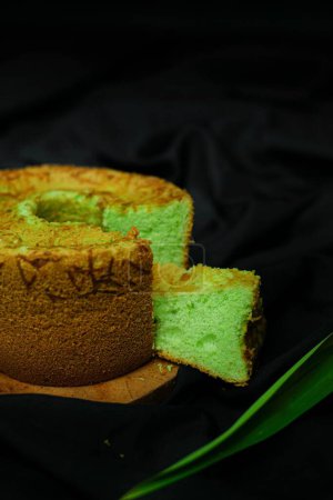 Téléchargez les photos : Un plan vertical de gâteau en mousseline de soie verte sur une planche de bois sur fond de tissu satiné noir - en image libre de droit