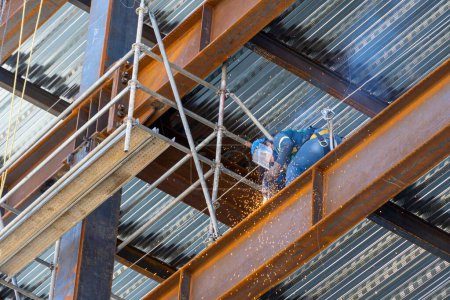 Foto de Un hombre soldando juntas de estructura de acero oxidado - Imagen libre de derechos