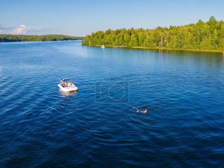 Foto de Un disparo de dron de un barco blanco en el mar y una persona haciendo esquí acuático - Imagen libre de derechos