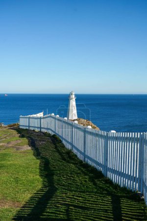 Téléchargez les photos : Un vieux phare en arrière-plan avec une clôture de piquet blanc immaculé au premier plan trouvé à St. John's, Terre-Neuve. - en image libre de droit