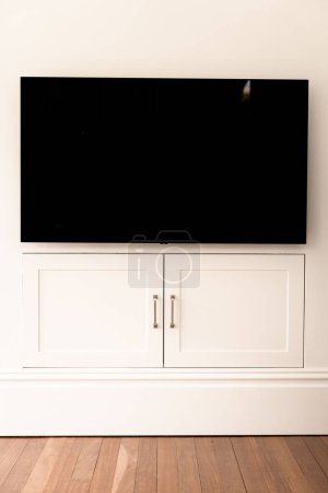 Foto de La toma vertical de una pantalla de TV moderna sobre las puertas de un armario blanco en la pared - Imagen libre de derechos