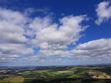 Téléchargez les photos : Une vue de drone des champs luxuriants de l'agriculture du haut de la colline sous le ciel bleu nuageux - en image libre de droit
