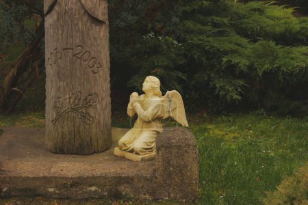 Foto de Iglesia de la Santísima Trinidad en Gierviaty. Una estatua de un pequeño ángel cerca de un árbol - Imagen libre de derechos