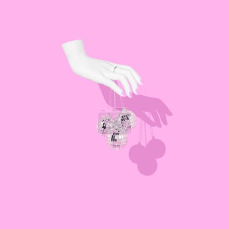 Photo for A woman's hand holding disco balls on pink background - Royalty Free Image