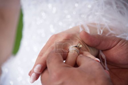 Téléchargez les photos : Un gros plan du marié mettant la bague sur le doigt de la mariée - en image libre de droit