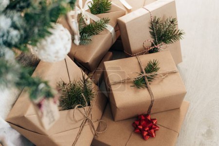 Téléchargez les photos : Cadeaux de Noël enveloppés dans du papier brun et sous l'arbre de Noël décoré - en image libre de droit