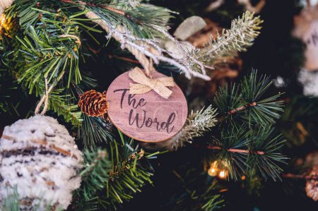 Téléchargez les photos : Gros plan d'un jouet en bois avec un mot "Le mot" sur un sapin de Noël décoré - en image libre de droit