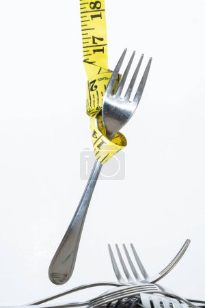 Photo for A closeup view of a hung fork with the sewing meter isolated on white background- concept of dieting - Royalty Free Image