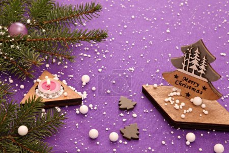 Photo for Christmas composition from a handmade wooden Christmas tree with the inscription "merry Christmas", candles and fir branches on a lilac background . - Royalty Free Image