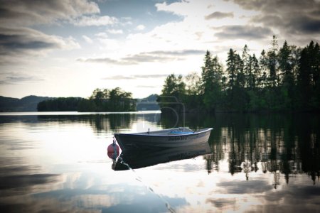 Téléchargez les photos : Un bateau garé dans un lac au coucher du soleil - en image libre de droit