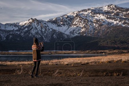 Téléchargez les photos : Une jeune femme photographiant la montagne enneigée dans les hautes terres - en image libre de droit