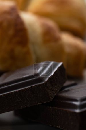 Foto de Un primer plano vertical de una barra de chocolate negro sobre un fondo de pastelería borroso - Imagen libre de derechos