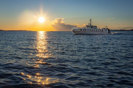 Téléchargez les photos : Un bateau de croisière naviguant sur la mer au coucher du soleil - en image libre de droit