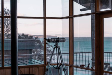 Photo for The view of a modern telescope placed by the windows in a waterside building - Royalty Free Image