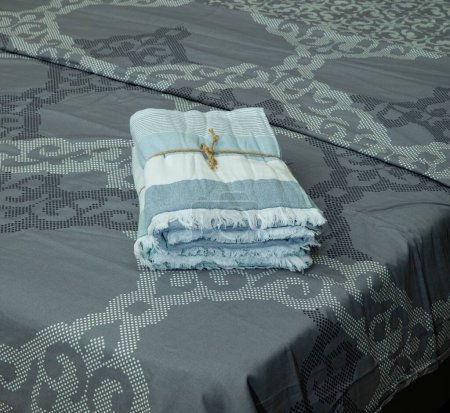 Téléchargez les photos : Un gros plan de serviettes de plage bleues blanches enveloppées de ficelle sur un lit - en image libre de droit