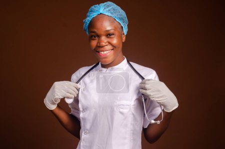 Foto de Una joven enfermera negra feliz mirando una cámara aislada sobre fondo marrón. - Imagen libre de derechos
