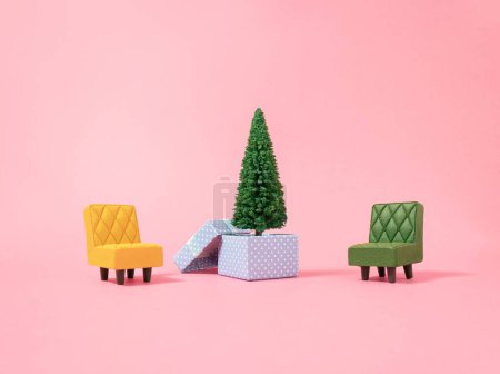 Téléchargez les photos : Les fauteuils jaunes et verts et un sapin de Noël dans une boîte cadeau isolé sur un fond rose. - en image libre de droit