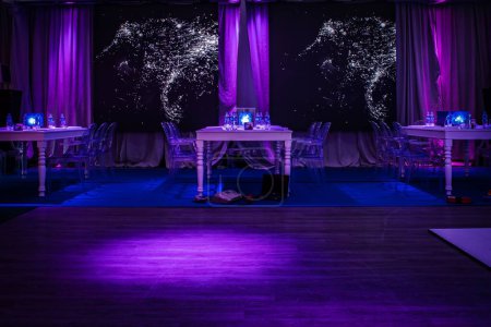Téléchargez les photos : Les tables de banquet joliment décorées avec des plats dans une salle éclairée par des néons - en image libre de droit