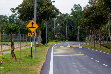 Téléchargez les photos : La courbe de la route avec des panneaux de signalisation "aller lent" réflexe arbres de lumière autour - en image libre de droit