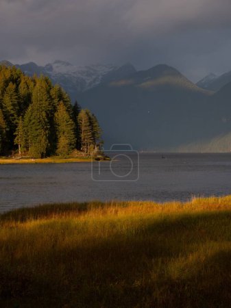 Foto de Un disparo vertical del lago Pitt con su orilla montañosa cubierta de abetos a la luz del atardecer - Imagen libre de derechos