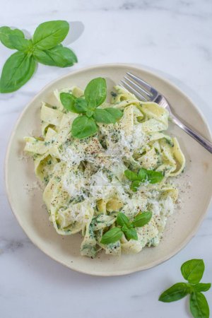 Photo for A vertical shot of a plate of pesto pasta with basil and parmesan cheese on the table - Royalty Free Image