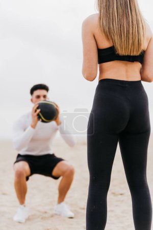 Photo for A young athletic male with a female doing back squats using a medicine ball - Royalty Free Image