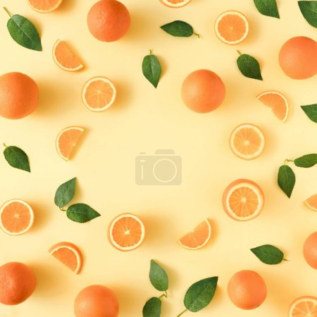 Foto de Un patrón de naranjas y hojas verdes sobre un fondo amarillo con un espacio de copia en el centro - Imagen libre de derechos