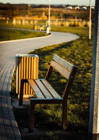 Photo for A vertical shot of a bench at a local park in Prague with a walkway in the blurred background - Royalty Free Image