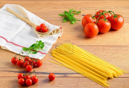 Téléchargez les photos : Un gros plan de pâtes italiennes avec de la vigne et des tomates cerises sur du bois - en image libre de droit