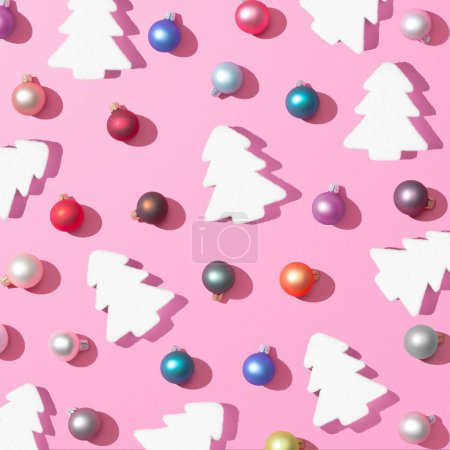 Foto de Una representación 3D del patrón de Navidad de moda hecha con adornos de bolas de colores y árboles de Navidad sobre fondo rosa, el concepto de Año Nuevo - Imagen libre de derechos