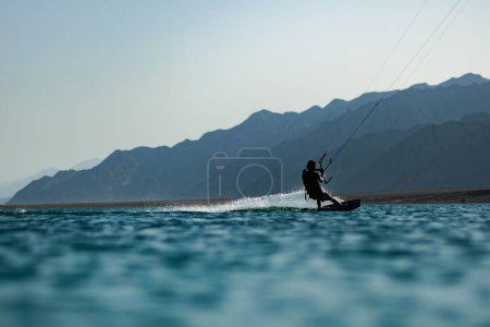 Foto de Una hermosa foto de un kitesurfista deslizándose sobre el agua de la laguna - Imagen libre de derechos