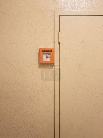 Foto de Un disparo vertical de un botón de ventilación de humo en alemán en una pared interior - Imagen libre de derechos