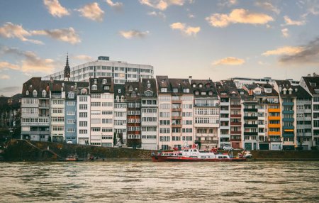 Téléchargez les photos : La vue sur le Rhin avec un bateau passant par le rivage avec des bâtiments colorés. Bâle, Suisse. - en image libre de droit