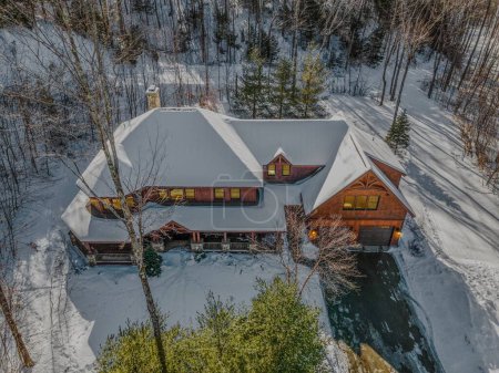 Photo for An aerial view of a wooden contemporary rustic house in the snowy mountains in the evening - Royalty Free Image
