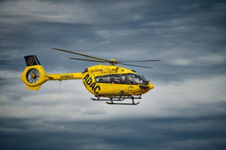 Photo for An ADAC helicopter flying in the background of dark clouds - Royalty Free Image