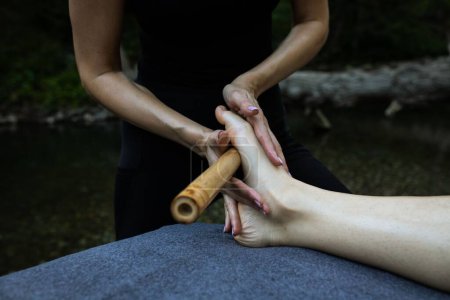 Téléchargez les photos : Un gros plan d'un massage professionnel relaxant des pieds avec un bâton de bois - en image libre de droit