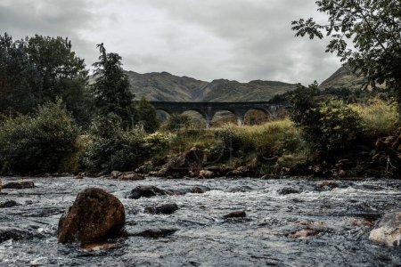 Téléchargez les photos : Un beau cliché du viaduc rocheux Glenfinnan près des montagnes verdoyantes en Écosse - en image libre de droit