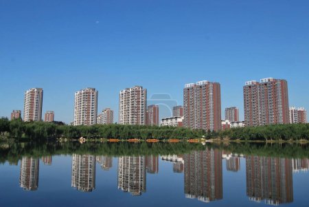Foto de Un lago rodeado de edificios altos con reflejos en el agua - Imagen libre de derechos