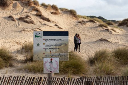 Photo for People ignoring nature protection and preservation sign walking on dunes with grass at cala mesquida spain. - Royalty Free Image