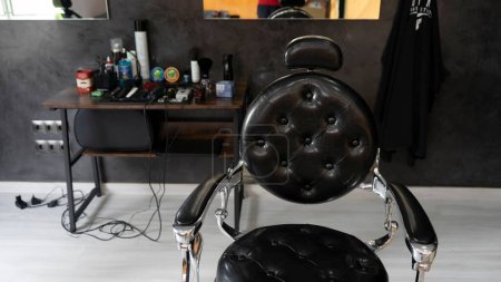 Foto de Un sillón de peluquería de cuero negro antiguo en una peluquería - Imagen libre de derechos
