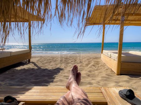 Téléchargez les photos : Un mâle pieds se prélassant au soleil sur la plage de sable - en image libre de droit
