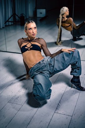 Téléchargez les photos : Une belle danseuse en mesh superposé crop top en pantalon noir et baggy posant sur le sol - en image libre de droit