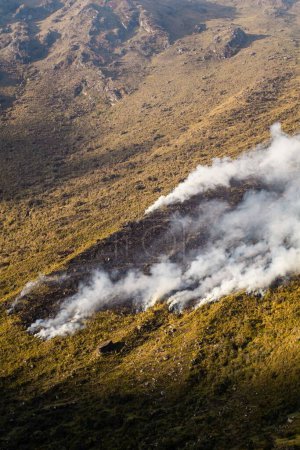 Téléchargez les photos : Un plan vertical de grands panaches de fumée de feu au sommet d'une montagne dans les Andes péruviennes - en image libre de droit