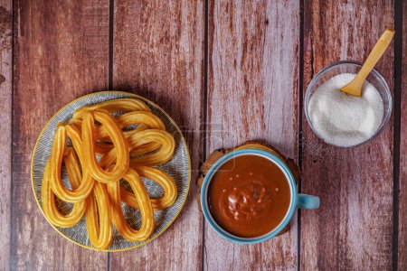 Photo for Hot chocolate with churros in a white and blue cup ,typical spanish breakfast on a wooden table - Royalty Free Image