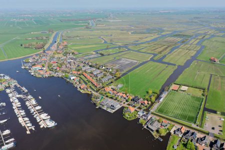Téléchargez les photos : Vue aérienne d'une ville avec de petits bâtiments et des champs avec une rivière et un port au milieu - en image libre de droit