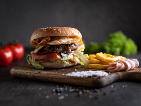 Téléchargez les photos : Un gros plan d'un hamburger avec des frites sur une planche de bois. - en image libre de droit