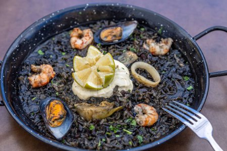 Photo for A closeup of Arros negre served on a pan in a restaurant - Royalty Free Image