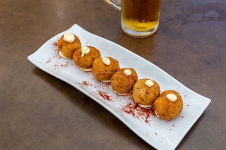 Photo for A closeup of fried mozzarella balls served with a glass of beer in a restaurant - Royalty Free Image